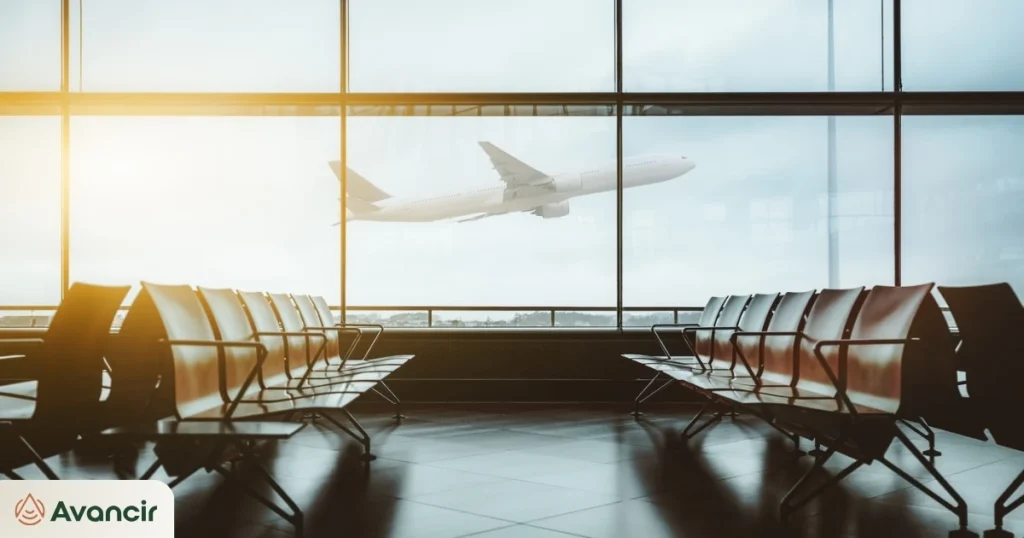 Airport departure gate lounge with an aircraft taking off beyond the window